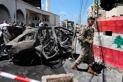Israeli drone strike in Lebanon: A Lebanese army soldier passes a damaged car